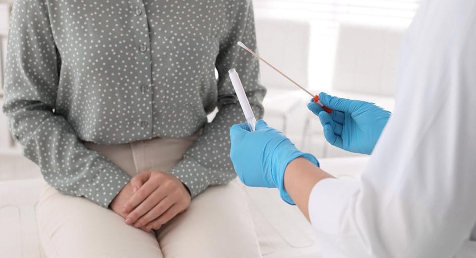 how to detect and treat STDs Doctor taking sample for STD testing from woman in clinic, closeup